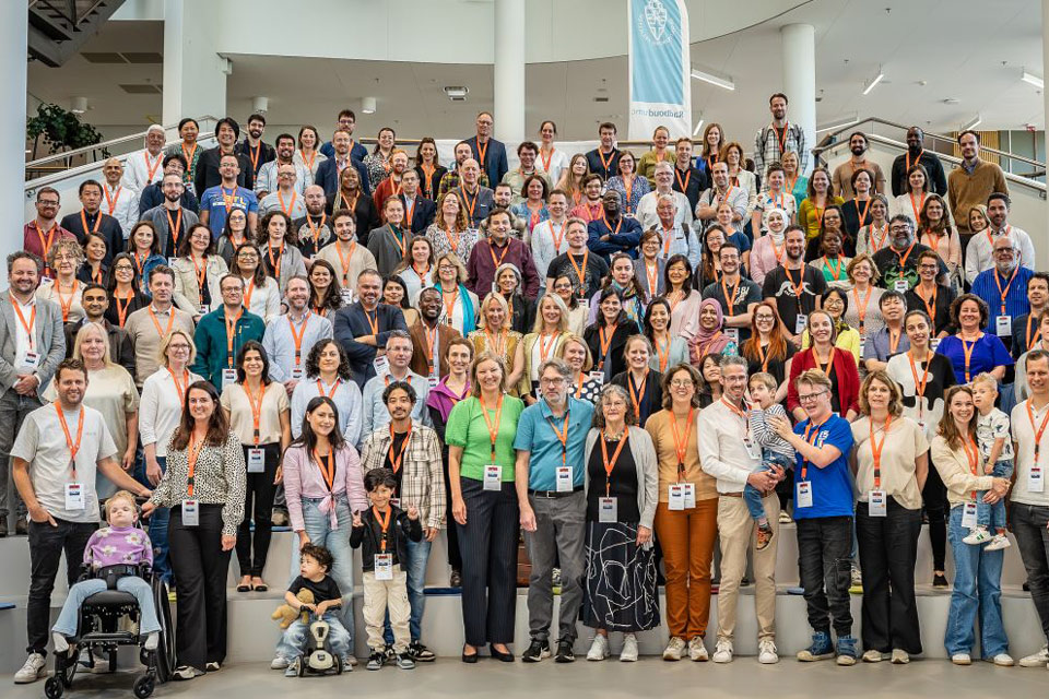 Group photo of around 150 collaborators, with families and children in front, standing on a large staircase at Radboud University Medical Center during the 2nd Undiagnosed Hackathon 2024