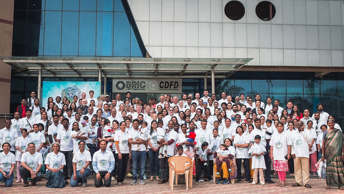 Group photo of the collaborators, families and children of the 4th Undiagnosed Hackathon in front of the BRIC-CDFD building in Hyderabad, India, February 2026